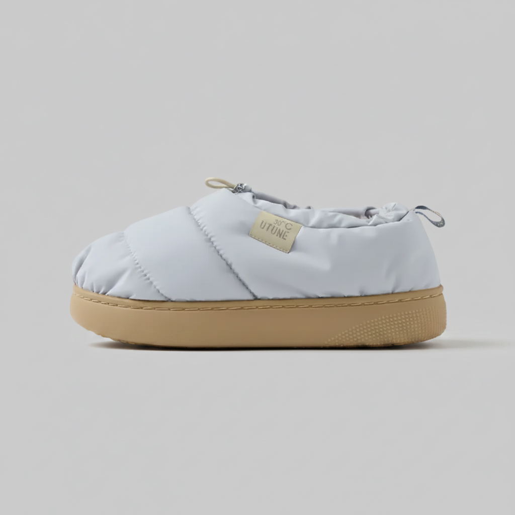 Light blue quilted slip-on shoe with tan sole on a white background