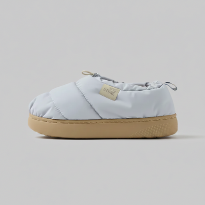 Light blue quilted slip-on shoe with tan sole on a white background