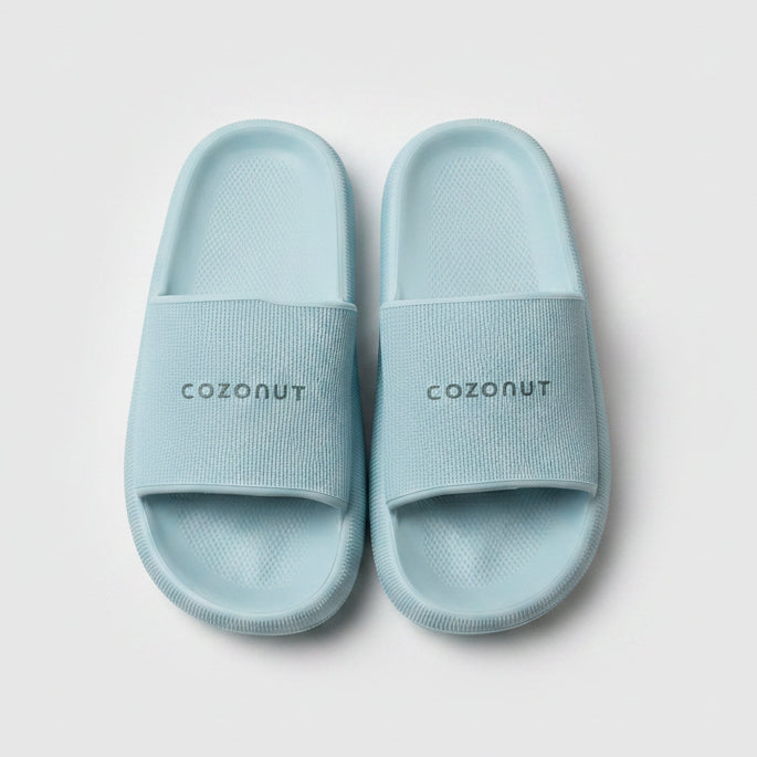 Pair of light blue slides with 'COZONUT' branding on a beige box.