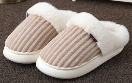 Pair of beige slippers with white fur lining on a brown carpet.