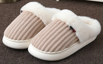 Pair of beige slippers with white fur lining on a brown carpet.