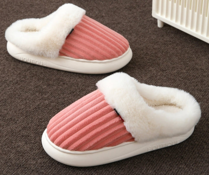 Pair of pink and white slippers on a brown floor.