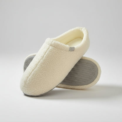 Pair of beige slippers with textured sole on a white background